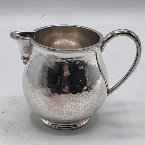 18 - Two matching sterling silver hand planished jugs together with matching hand planished sterling silv... 