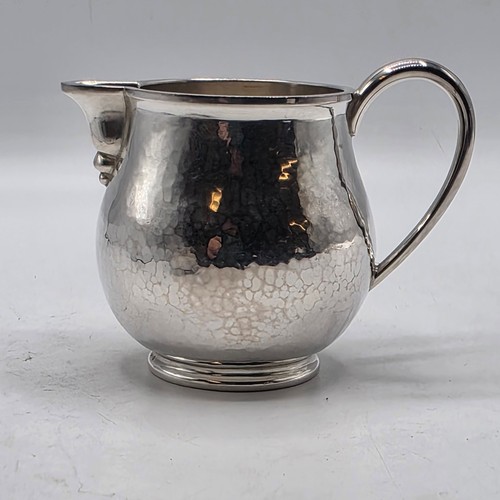 18 - Two matching sterling silver hand planished jugs together with matching hand planished sterling silv... 