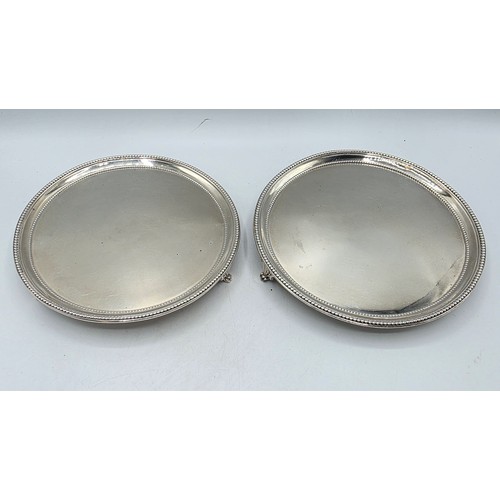 54 - A pair of sterling silver circular card trays or salvers with beaded rims on three shell feet.   Joh... 