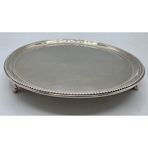 54 - A pair of sterling silver circular card trays or salvers with beaded rims on three shell feet.   Joh... 