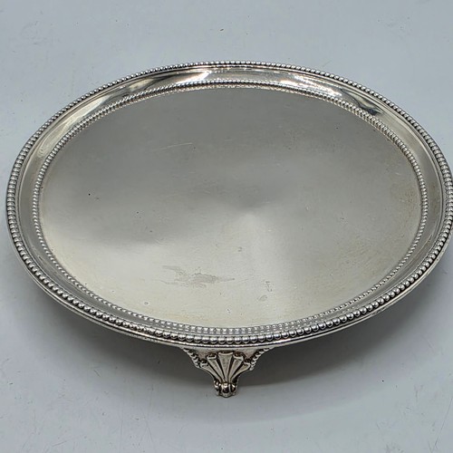 54 - A pair of sterling silver circular card trays or salvers with beaded rims on three shell feet.   Joh... 