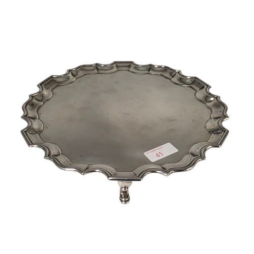 45 - A sterling silver card tray or salver with pie crust rim raised on three hoof feet. 26cm (d). By Jos... 