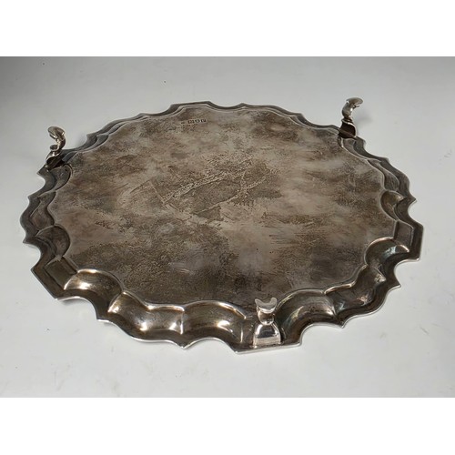 45 - A sterling silver card tray or salver with pie crust rim raised on three hoof feet. 26cm (d). By Jos... 