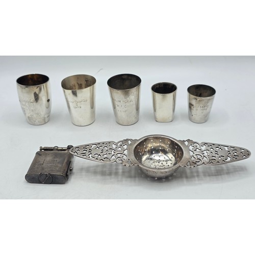 56 - A collection of white metal beakers and a Dunhill white metal engine turned cigarette lighter togeth... 