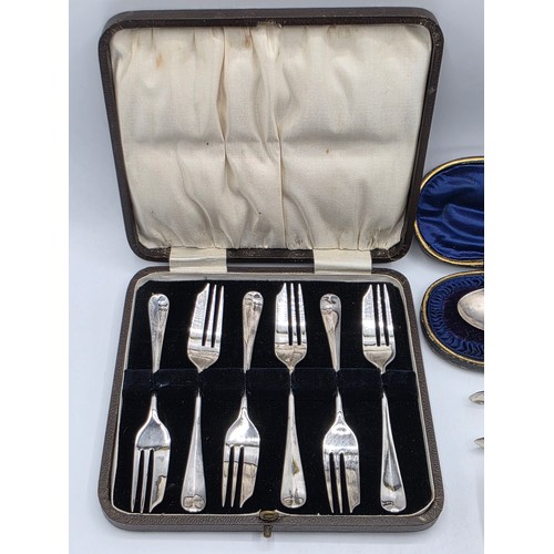 55 - A boxed set of sterling silver cake forks together with a boxed sterling silver christening spoon an... 