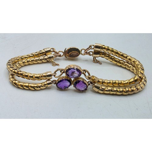 53 - An unmarked yellow metal and amethyst double snake link bracelet set with four free cut oval amethys... 