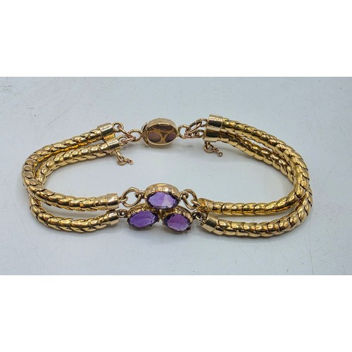 53 - An unmarked yellow metal and amethyst double snake link bracelet set with four free cut oval amethys... 