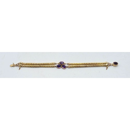 53 - An unmarked yellow metal and amethyst double snake link bracelet set with four free cut oval amethys... 