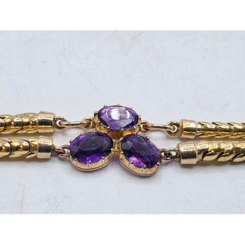 53 - An unmarked yellow metal and amethyst double snake link bracelet set with four free cut oval amethys... 