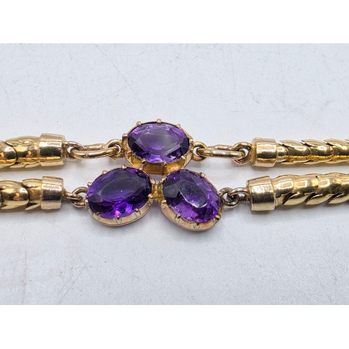 53 - An unmarked yellow metal and amethyst double snake link bracelet set with four free cut oval amethys... 