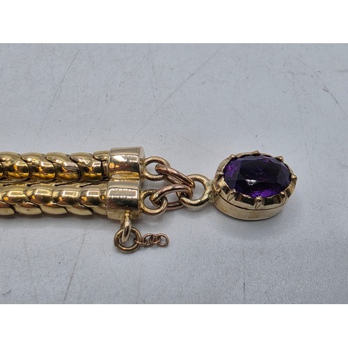 53 - An unmarked yellow metal and amethyst double snake link bracelet set with four free cut oval amethys... 