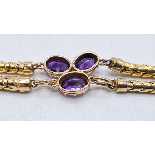 53 - An unmarked yellow metal and amethyst double snake link bracelet set with four free cut oval amethys... 