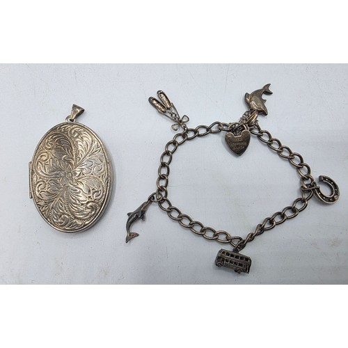 26 - A sterling silver charm bracelet togethjer with an oval locket with chased decoration. Gross weight ... 