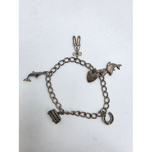 26 - A sterling silver charm bracelet togethjer with an oval locket with chased decoration. Gross weight ... 