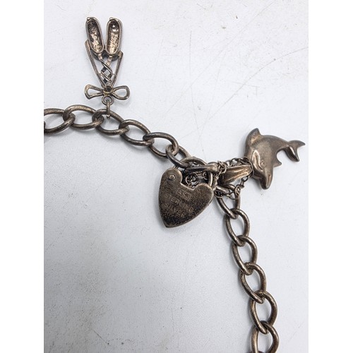 26 - A sterling silver charm bracelet togethjer with an oval locket with chased decoration. Gross weight ... 