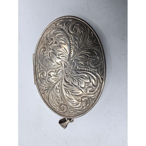 26 - A sterling silver charm bracelet togethjer with an oval locket with chased decoration. Gross weight ... 