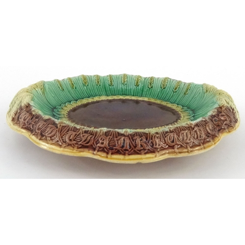 711 - Victorian Majolica pottery bread plate decorated with wheatsheaves and script, 32cm diameter
