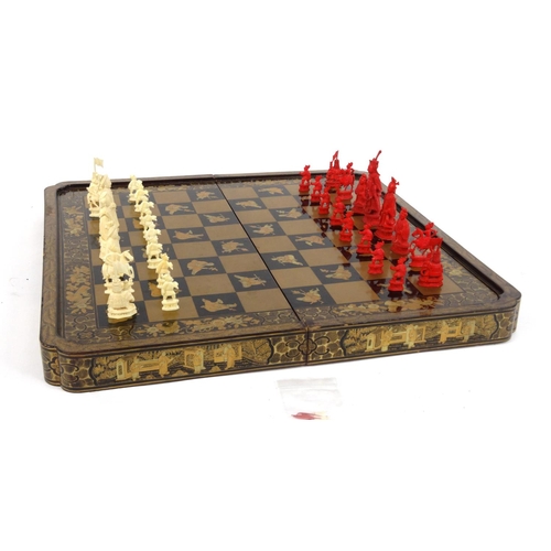 604 - Oriental chinese carved ivory chess set together with a folding black lacquered chess/backgammon boa... 