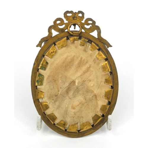 219 - Portrait miniature of a girl wearing a bonnet, housed in a brass swag design frame, 10cm high