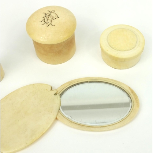 30 - Three ivory screw top containers, together with an ivory hand mirror, the hand mirror 11cm long when... 