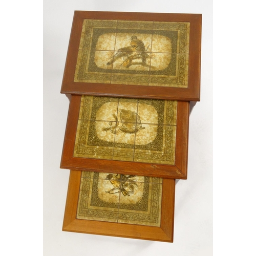 43 - Nest of three teak tile top occasional tables decorated with falcons, the largest 47cm high