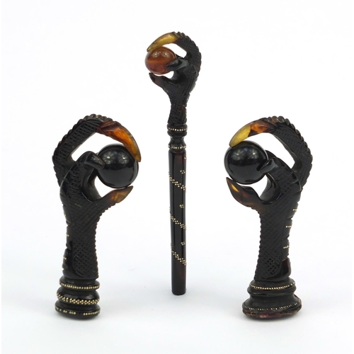 106 - Two tortoiseshell effect claw and ball seals, together with a similar example all inlaid with gold m... 