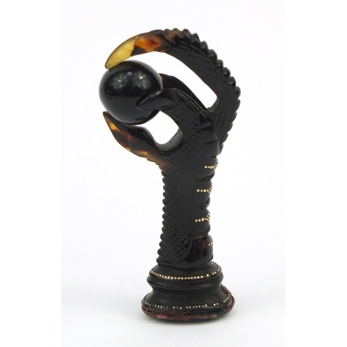 106 - Two tortoiseshell effect claw and ball seals, together with a similar example all inlaid with gold m... 