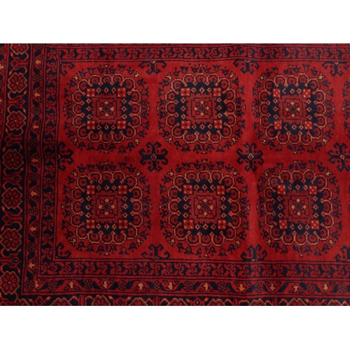 2035 - Rectangular Middle Eastern Qalin rug decorated with geometric shapes onto a red ground, 143cm x 105c... 