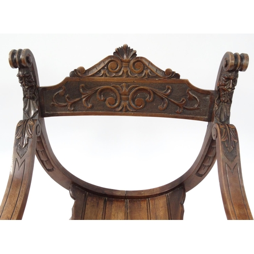 2034 - Carved wooden X-framed chair with face finials, 85cm high