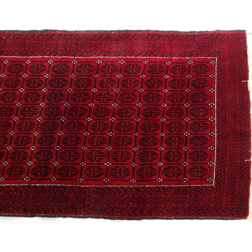 38 - Red and black ground geometric patterned rug, 206cm x 106cm