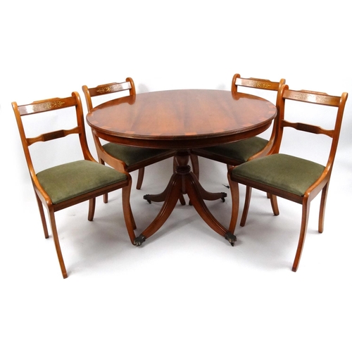 108 - Circular yew wood snap top dining table and four chairs with brass inlay, the table 76cm high x 107c... 