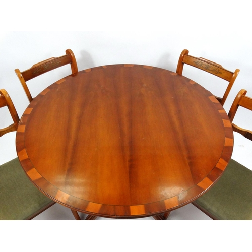 108 - Circular yew wood snap top dining table and four chairs with brass inlay, the table 76cm high x 107c... 