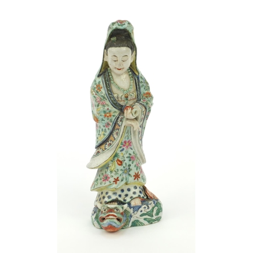 562 - Oriental Chinese stoneware figure standing on a mythical beast, the robe hand painted with flowers, ... 