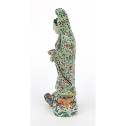 562 - Oriental Chinese stoneware figure standing on a mythical beast, the robe hand painted with flowers, ... 