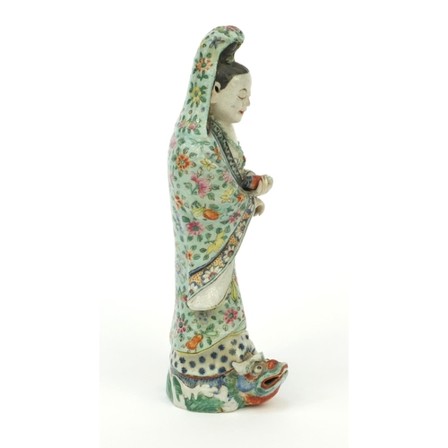 562 - Oriental Chinese stoneware figure standing on a mythical beast, the robe hand painted with flowers, ... 