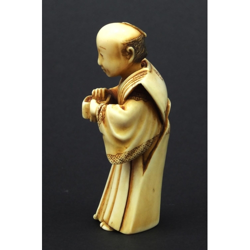 612 - Oriental Japanese ivory Netsuke of a robed elder holding a pot, with moveable head, 5cm high