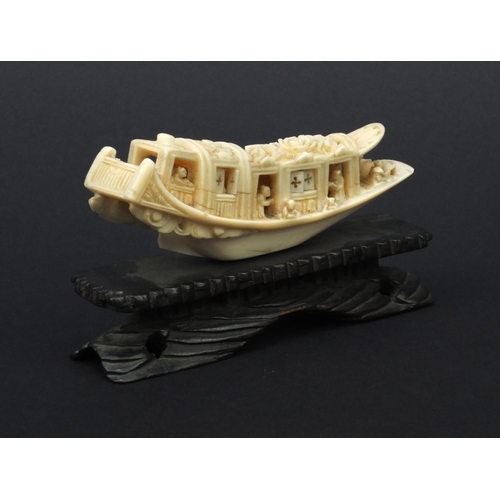 615 - Oriental carved ivory model of a junk, the roof carved with flowers, raised on a wooden base, 5.5cm ... 