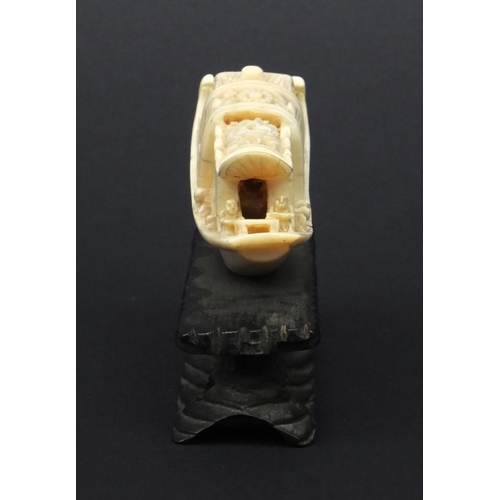 615 - Oriental carved ivory model of a junk, the roof carved with flowers, raised on a wooden base, 5.5cm ... 