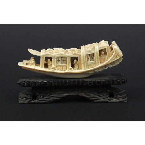 615 - Oriental carved ivory model of a junk, the roof carved with flowers, raised on a wooden base, 5.5cm ... 