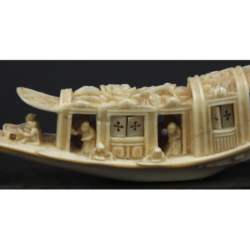 615 - Oriental carved ivory model of a junk, the roof carved with flowers, raised on a wooden base, 5.5cm ... 