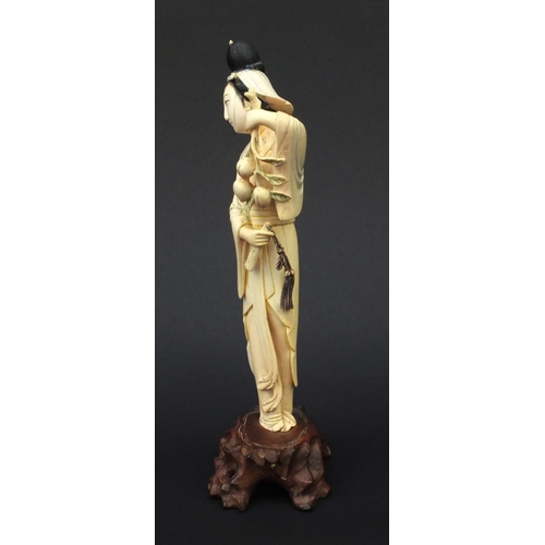 604 - Oriental ivory carved okimono of a girl holding flowers and wearing a robe, raised on a hardwood bas... 