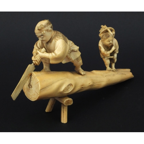 599 - Oriental Japanese carved ivory okimono of an elder and child standing on a tree trunk, the elder cut... 