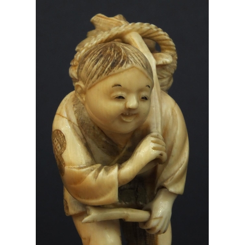 599 - Oriental Japanese carved ivory okimono of an elder and child standing on a tree trunk, the elder cut... 