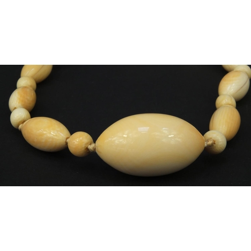 628 - Ivory beaded necklace and an ivory backed clothes brush, the largest bead 4cm diameter