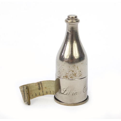 101 - Sewing interest tape measure and thimble holder in the form of a wine bottle, 7cm high