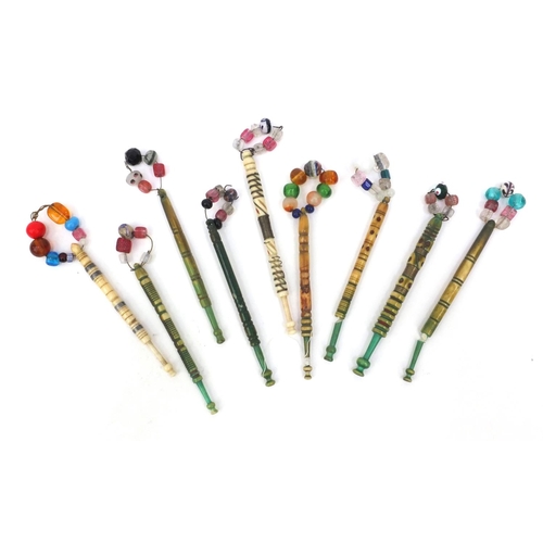 94 - Nine sewing interest antique bone lace bobbins with beaded glass tops, the largest 12cms long