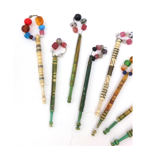 94 - Nine sewing interest antique bone lace bobbins with beaded glass tops, the largest 12cms long