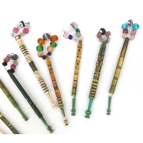 94 - Nine sewing interest antique bone lace bobbins with beaded glass tops, the largest 12cms long