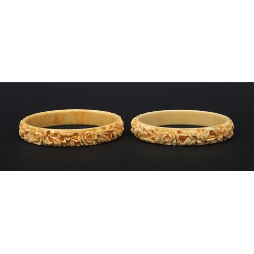 629 - Two oriental Chinese ivory bangles both carved with flowers, each 7.5cm diameter