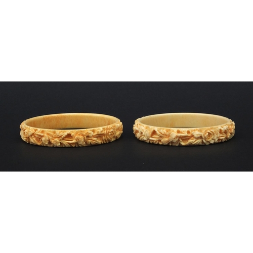 629 - Two oriental Chinese ivory bangles both carved with flowers, each 7.5cm diameter